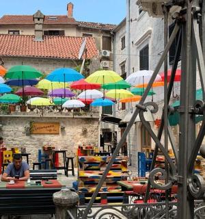 一位男士坐在桌边，桌边摆放着五彩缤纷的遮阳伞