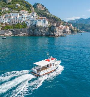 a boat in the water with a town on a hill