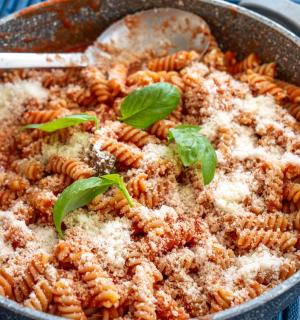 a pan of pasta with a spoon and basil on it