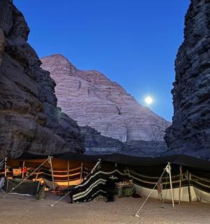 a tent in a canyon with the moon behind it