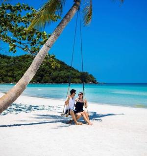 two women sitting on a swing on a beach