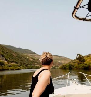 a woman standing on the front of a boat on a river