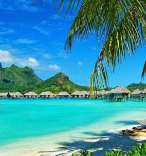 a beach with boats and huts in the water