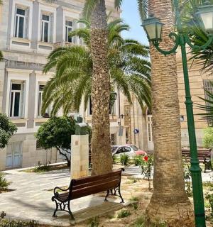a park with a bench and palm trees and a building