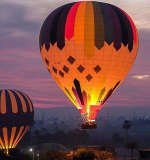 two hot air balloons flying in the sky at dusk