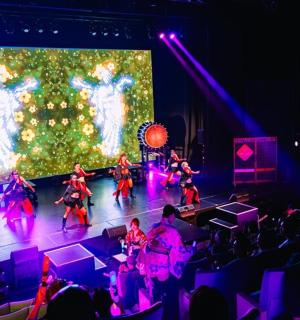 一群表演者在圣诞树前的舞台上