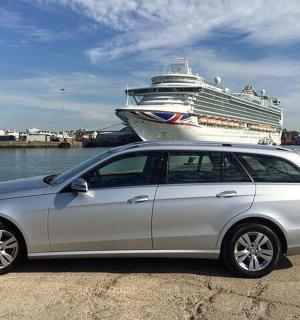 a silver car parked in front of a cruise ship