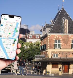 a hand holding a cell phone in front of a building