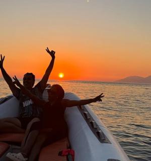 two people sitting in a boat in the ocean at sunset