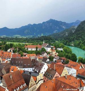 a town with red roofs and a river and mountains