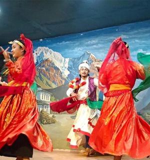 three women performing a folk dance in front of a mural