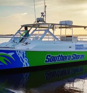a boat sitting in the water with the sun setting