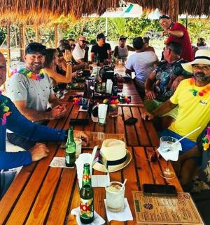 un grup de persones assegudes al voltant d'una llarga taula de fusta