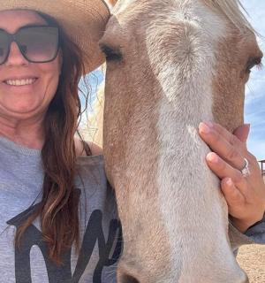 a woman wearing a cowboy hat standing next to a horse
