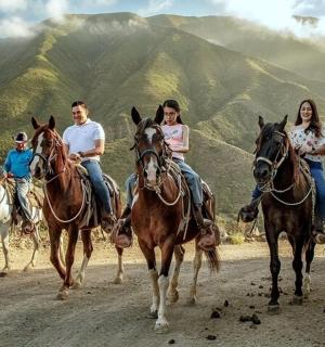 a group of people riding horses down a dirt road