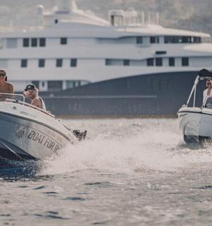 skupina lidí v lodích ve vodě s jachtou