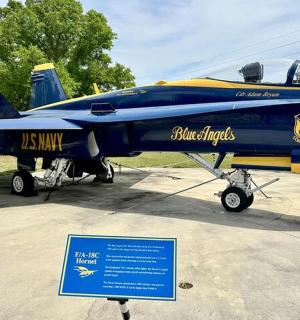 一架蓝黄相间的战斗机在展台上展示着一个标志