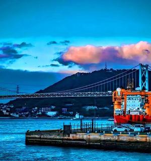 an orange boat is docked next to a bridge