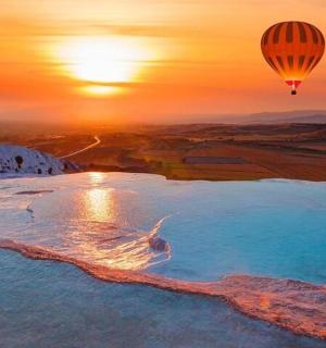 a hot air balloon flying over a lake at sunset