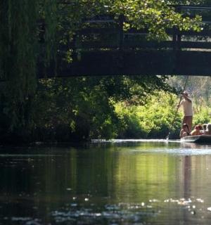 一名男子站在桥下水中的船上