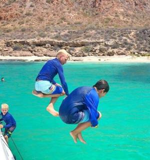 two men jumping off of a boat in the water