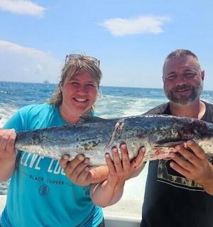 a man and a woman holding a large fish