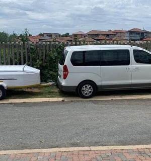 一辆白色货车停在围栏旁边，旁边还有一辆拖车