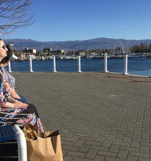 一位女士坐在水边的长椅上