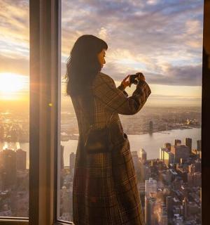 a woman standing in a window taking a picture of the city