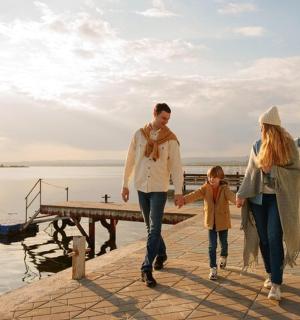 a family walking on a dock by the water