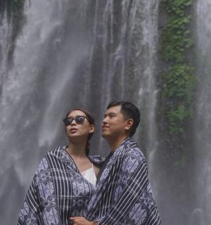a man and woman standing in front of a waterfall