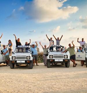 skupina lidí stojící na střechách svých džípů