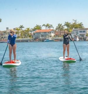 Dvě ženy stojí na paddleboardech ve vodě