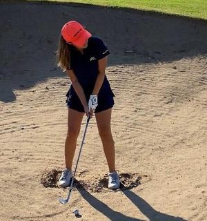 mladá žena hrající golf v hlíně