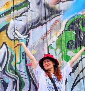 a woman standing in front of a wall covered in graffiti