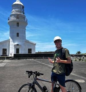 muž stojící vedle kola před majákem