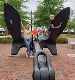 two women and two children standing on a whale statue