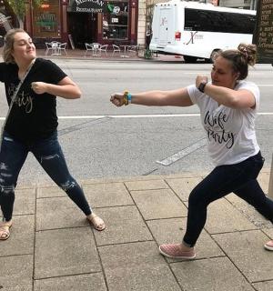 two women are dancing on a city street