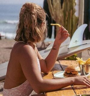 一位女士坐在桌边,手里拿着三明治和冲浪板