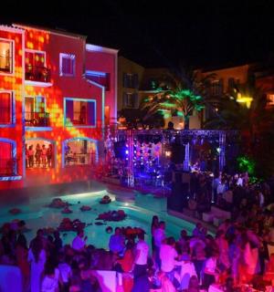 a crowd of people standing around a swimming pool at night