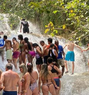 a group of people in the water at a waterfall