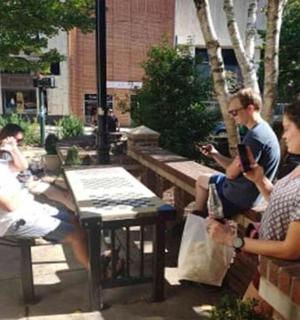 skupina lidí sedících na lavičkách v parku