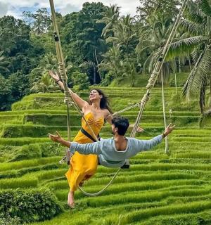Muž a žena na lanové houpačce nad rýžovým polem