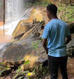 a young man standing in front of a waterfall
