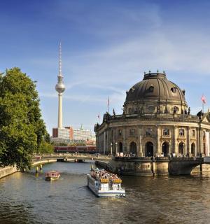 a boat in a river with a building and a bridge