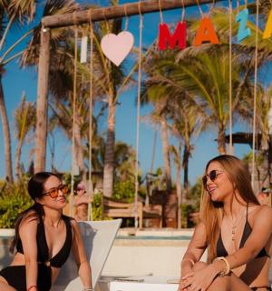 two women in bathing suits sitting at a table on the beach
