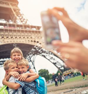 a woman holding two children in front of the eiffel tower