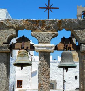 two bells on a tower with a church