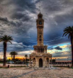 hodinová věž s palmami a zamračenou oblohou