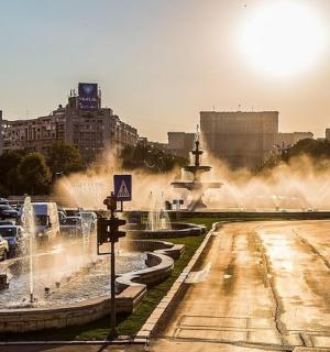 a city with a fountain in the middle of a street